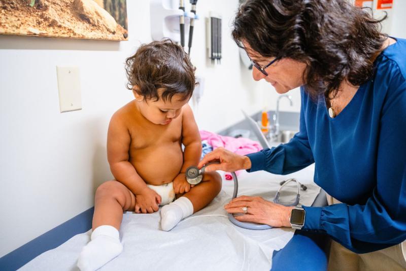 a pediatrician holding a stethoscope against a young boy